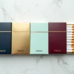 Rangée de paquets de cigarettes Vogue de différentes couleurs sur marbre blanc, vue de dessus